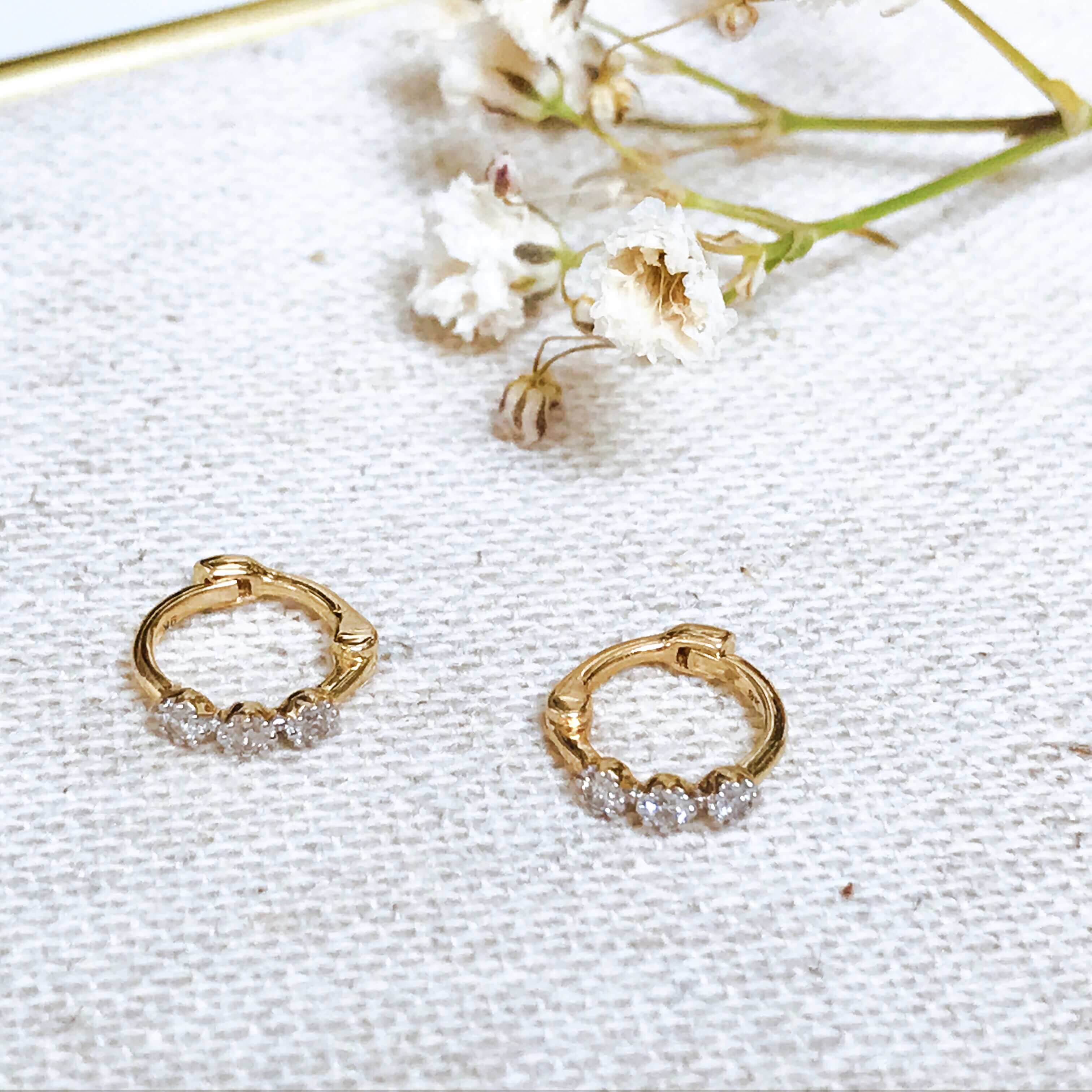 Mini Diamond Trilogy Huggie Hoop Earring pair 9k Gold on fabric 