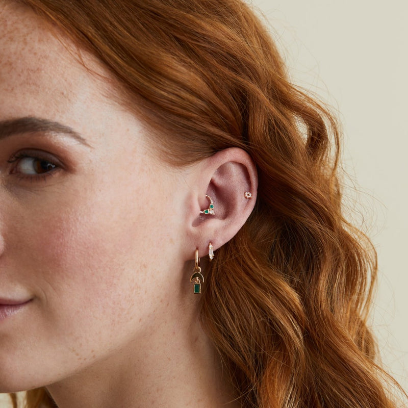 model wearing an earring stack featuring daith earings made with emerald, diamond & 9 karat gold hoops